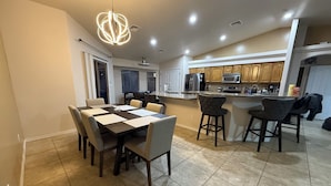 A modern kitchen with wooden cabinets, a central island, and a dining area with a table and chairs.