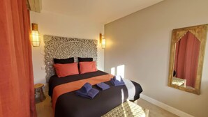 A bedroom with a large bed, two wall-mounted lamps, a decorative headboard, and a mirror with a gold frame. - Typical house with pool and garden, quiet parking - Saintes Les Cuves (Chaniers)