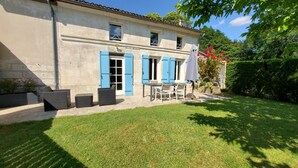 A two-story house with a patio area featuring outdoor furniture and a table. - Typical house with pool and garden, quiet parking - Saintes Les Cuves (Chaniers)