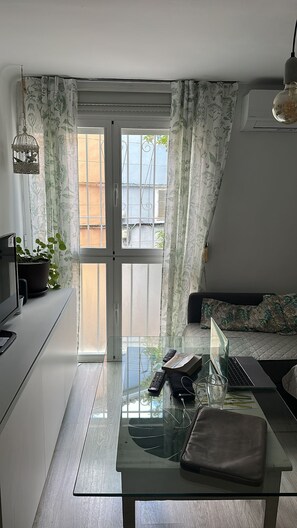 A modern kitchen with a glass dining table, a laptop, and a remote control. - Apartment near the Palacio de Congresos   (Granada Centro)