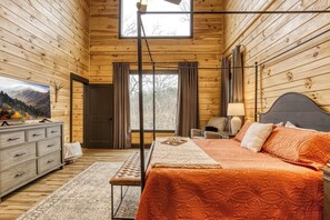 A wooden cabin bedroom with a bed, dresser, and a large window. - Romantic Smoky Mt Cabin-Hot Tub|Fire Pit|Location! (Sevierville)