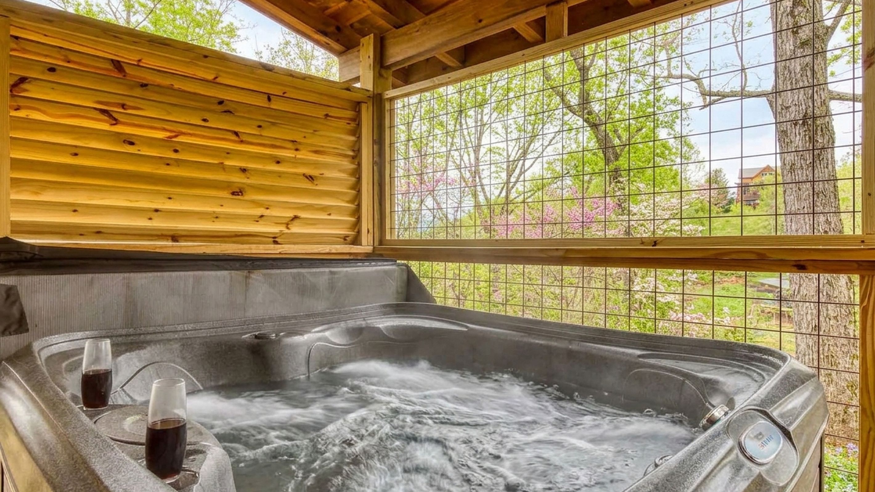 A hot tub with two glasses of a dark liquid, likely a beverage, inside.