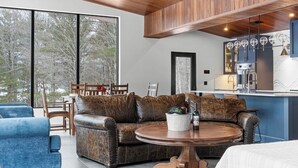 A modern living room with a leather sofa, a round wooden coffee table, and a dining area with a wooden table and chairs.