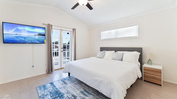 A bedroom with a bed, a ceiling fan, a TV, a window with blinds, and a nightstand with a lamp. - 3-bedroom house in gorgeous Bakersfield with Balcony & Large Yard (Bakersfield)