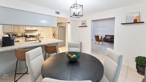 A modern kitchen with a central island, a dining area with a round table and chairs, and a living room with a sofa and chairs. - 3-bedroom house in gorgeous Bakersfield with Balcony & Large Yard (Bakersfield)