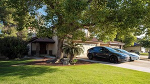 A residential house with a driveway, two cars parked, and a well-maintained lawn. - 3-bedroom house in gorgeous Bakersfield with Balcony & Large Yard (Bakersfield)