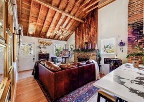 Un salon chaleureux avec un canapé en cuir, une cheminée en pierre et un plafond en bois.