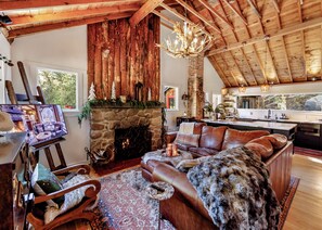 Un interior rústico con chimenea de piedra, muebles de cuero y techo de madera.