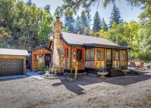 Ein rustikales Blockhaus mit einem Steinofen, einer Garage und einer Terrasse mit Topfpflanzen.
