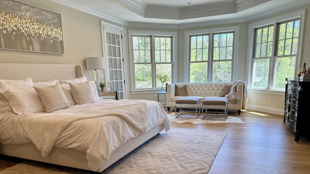 Une chambre à coucher avec un grand lit, une chaise longue et une commode.