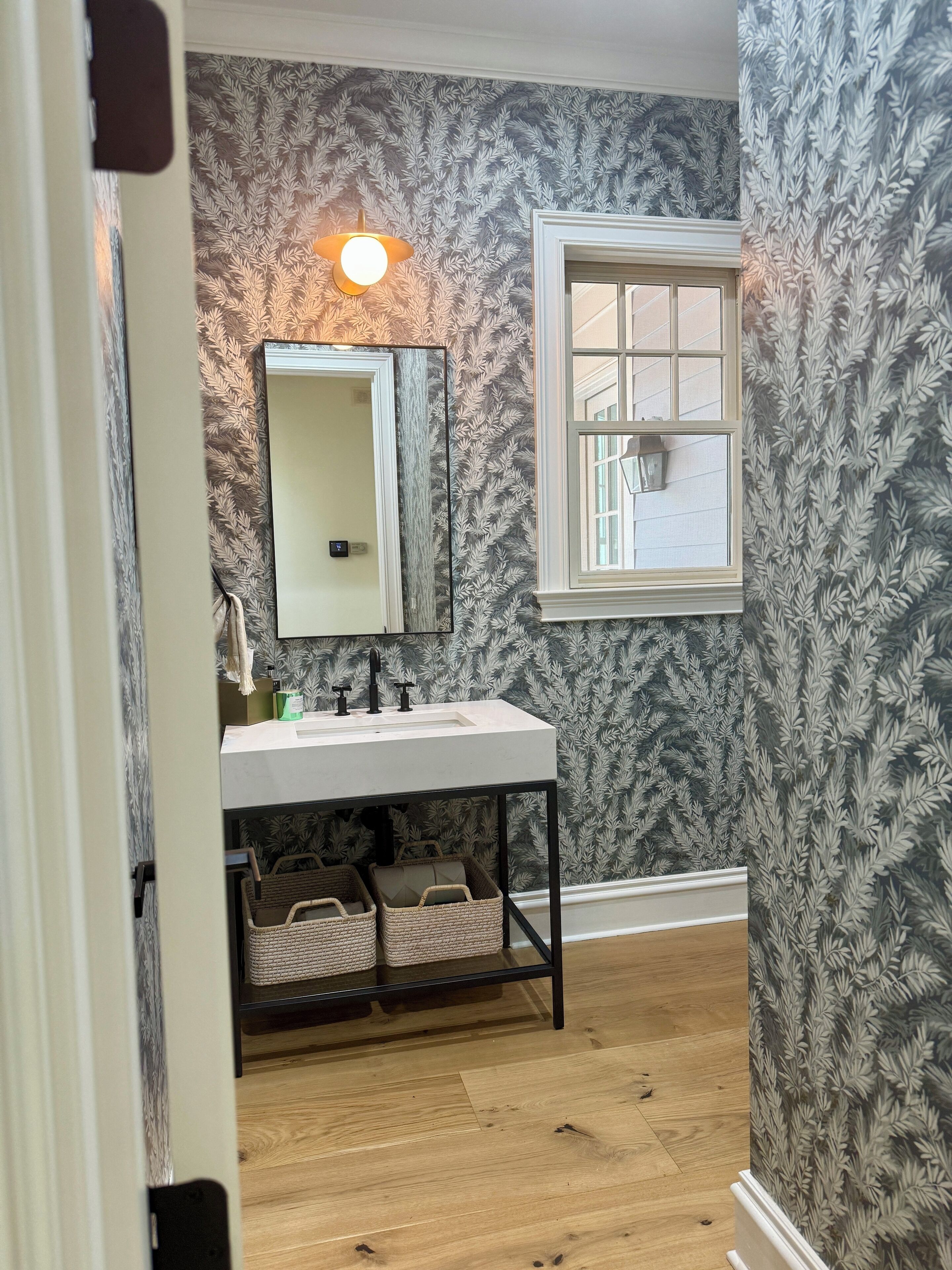 A bathroom with a white sink, mirror, and frosted glass window.