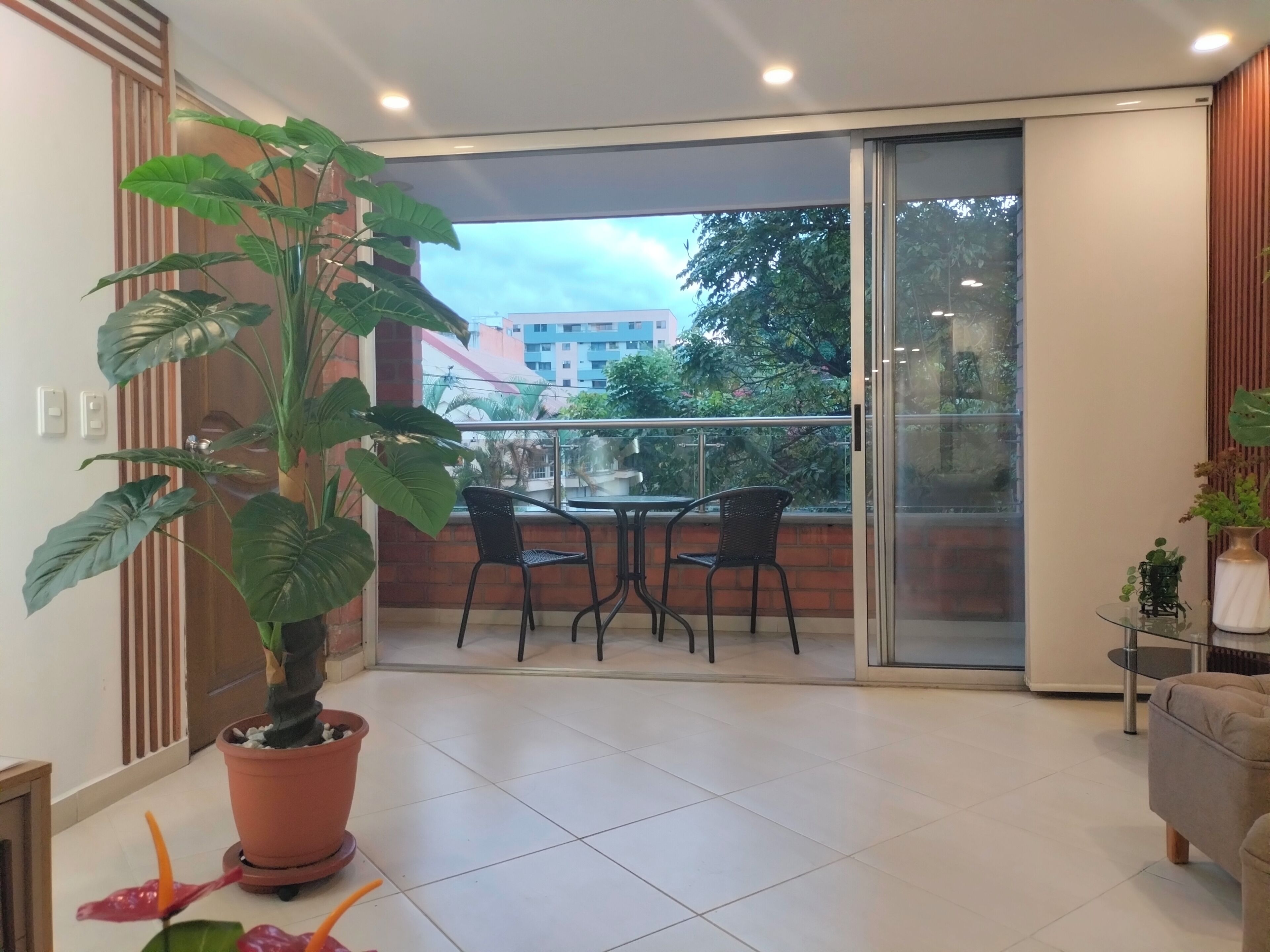 Ein Balkon mit einem Blumentopf, zwei Stühlen und einem Tisch.
