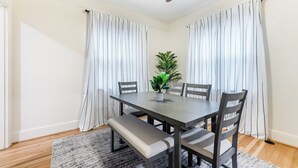 Ein Essbereich mit Tisch, Stühlen, einer Bank, einem Deckenventilator und einem Blumentopf.