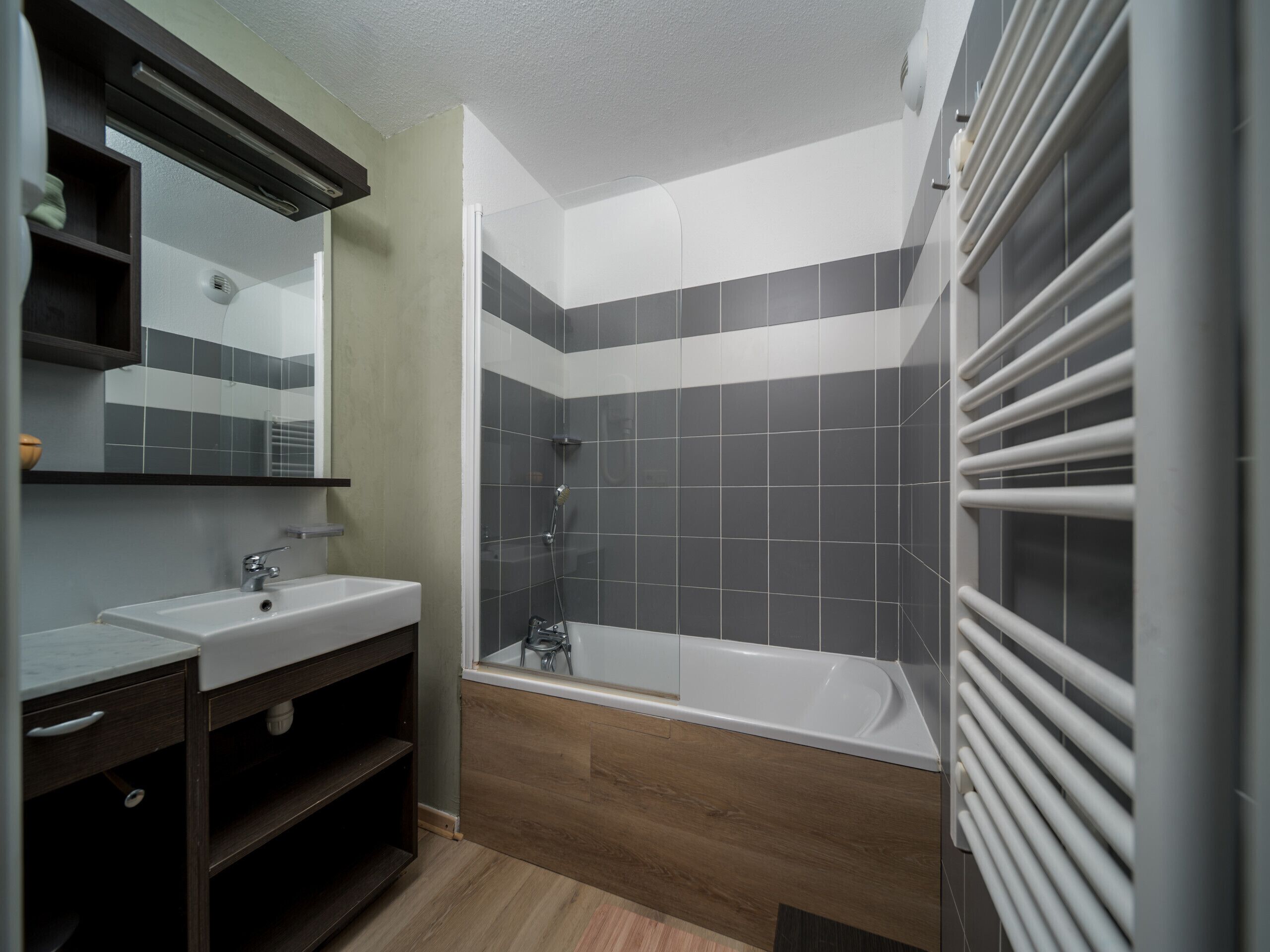 Une salle de bain moderne avec une douche, un lavabo et un miroir.