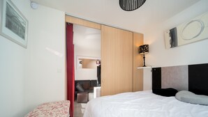 Ein Hotelzimmer mit Bett, Schreibtisch, Stuhl und einem roten Vorhang.