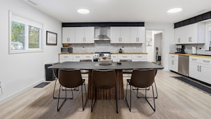 A modern kitchen with white cabinets, a central island, and a large window. - Beach Access + Hot Tub | Near Tamarack & McCall (Donnelly)