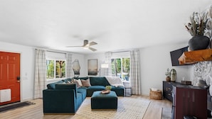 A living room with a sectional sofa, ottoman, and a ceiling fan. - Beach Access + Hot Tub | Near Tamarack & McCall (Donnelly)
