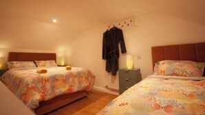 Ein Schlafzimmer mit zwei Betten, jeweils mit floraler Bettwäsche, einem Holz-Kopfteil und einem Nachttisch mit Lampe.
