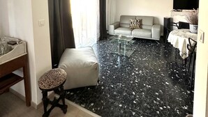 Un salon comprenant un canapé, une table basse en verre, une table à manger avec des chaises, un téléviseur et un luminaire au plafond.