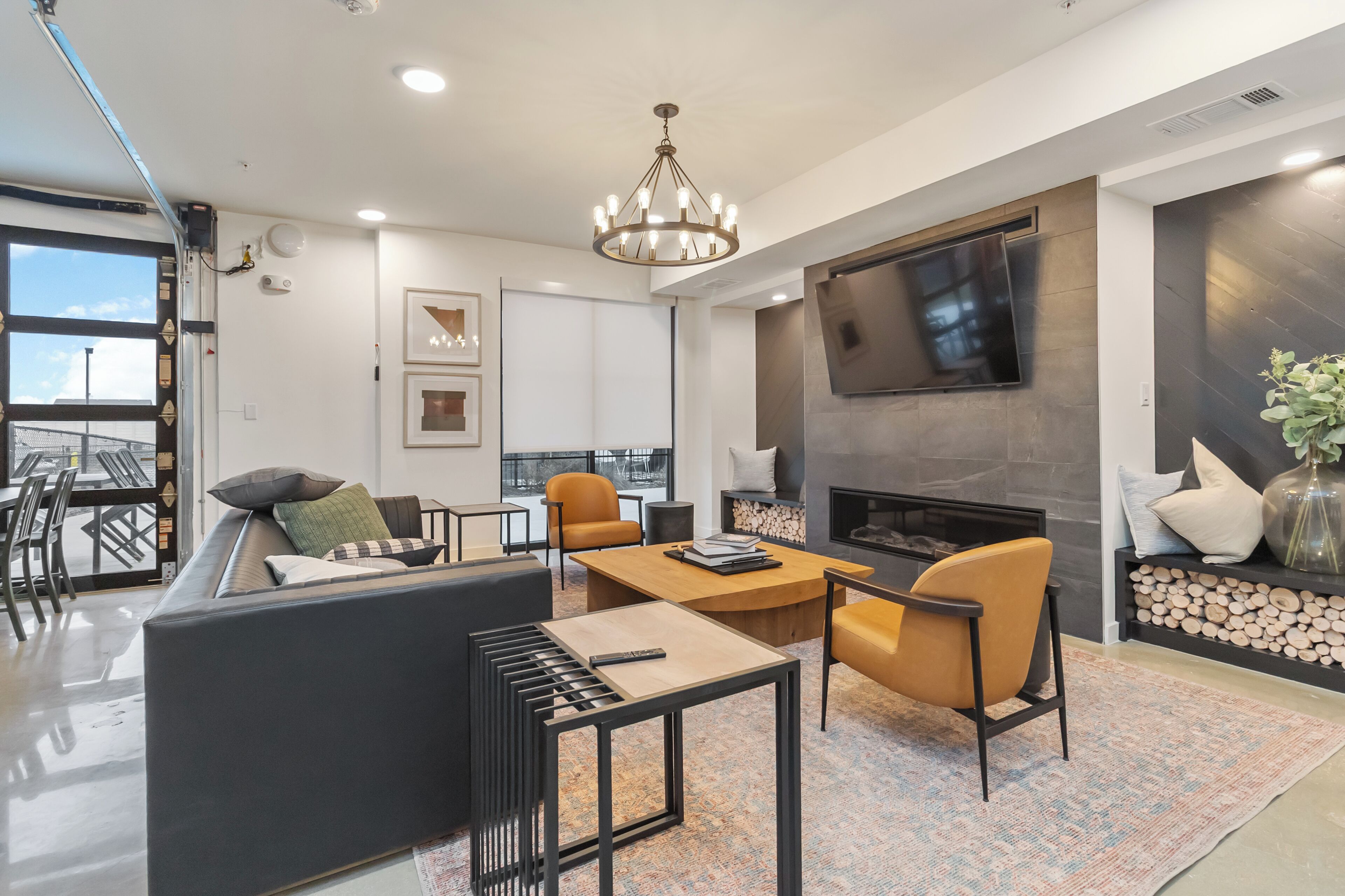 A modern living room with a sofa, chairs, a coffee table, a fireplace, and a TV mounted on the wall.
