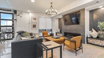 A modern living room with a sofa, chairs, a coffee table, a fireplace, and a TV mounted on the wall.