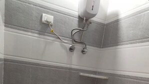 Un baño pequeño y estrecho con un inodoro, un secamanos y un dispensador de jabón fijado a la pared.