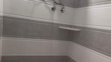 Een douche, handdoeken, zeep, toiletpapier