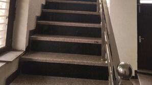 Una escalera con barandilla de metal y una puerta al final.