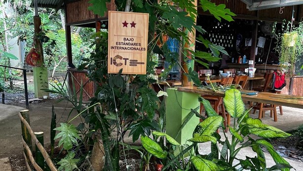 A restaurant with a sign indicating it meets international standards, surrounded by lush greenery and a rustic wooden fence. - Independent Cabin for 4 Guests – Casa Tucán Tranquilo, Gandoca (Gandoca)
