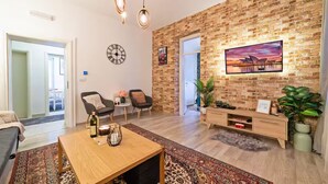 Un salon moderne avec un mur en briques, un téléviseur à écran plat, une table basse en bois et un canapé.