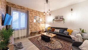Un salon moderne avec un mur en briques, un canapé avec des coussins, une table basse et un téléviseur fixé au mur.