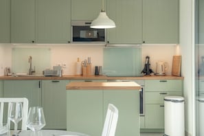 A modern kitchen with light green cabinets, a wooden countertop, and a hanging pendant light. - Elegant 2 bed Apt. private parking, Close to Gare, Valleen Telecabine & Thermes (Saint-Gervais-les-Bains)