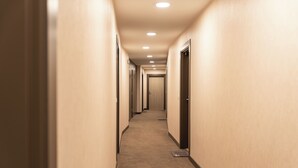 Um corredor longo e estreito com portas em ambos os lados, que leva a um quarto no final.