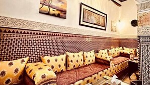 A cozy lounge area with a patterned sofa, decorative pillows, and a ceiling fan. - Patrimoine de Fes  (Fès)