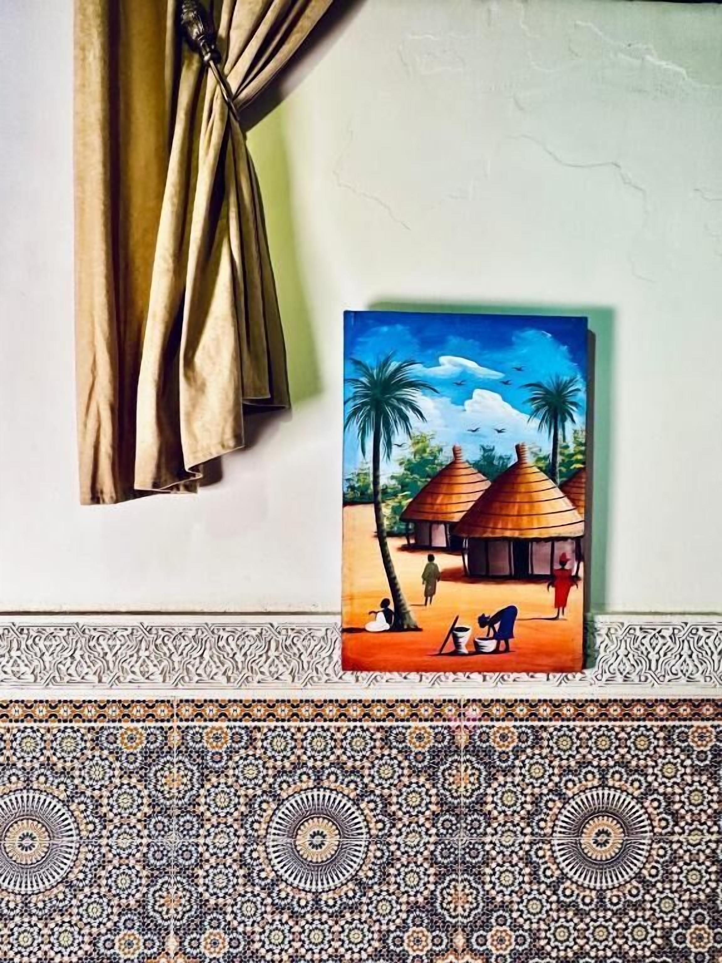 A room with a painting of a tropical scene, a patterned border, and a curtain.