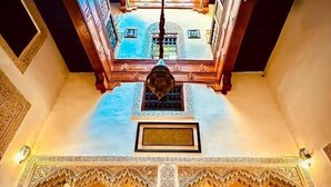 A high-ceilinged interior with ornate arches and a central column, featuring a view of a building through a skylight. - Patrimoine de Fes  (Fès)