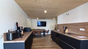 Eine moderne Küche mit Holzboden, einer eingebauten Kochinsel und einem flachbildfernseher an der Wand.