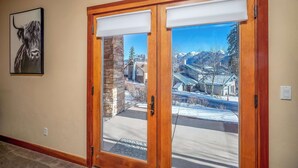 Una puerta de madera con vistas a un paisaje nevado de montañas a través de un panel de vidrio.