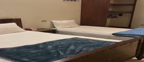 Un dormitorio con dos camas individuales, un armario de madera y una mesita.