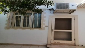 Um quarto com janela, ar condicionado e porta.