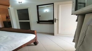 Quarto com uma cama, uma porta, um espelho e uma televisão.