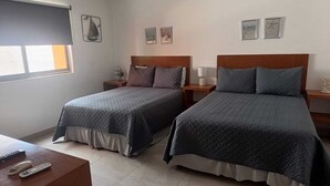 Habitación de hotel con dos camas, un escritorio y una ventana con persianas.