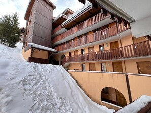 A multi-story building with wooden balconies and snow-covered ground. - Warm and cozy apartment, 250 m from the slopes, fully renovated, sleeps 6 (La Plagne Tarentaise)