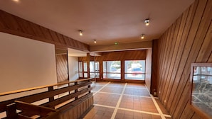 A spacious hallway with wooden paneling and a tiled floor, leading to large windows with a view of parked cars outside. - Warm and cozy apartment, 250 m from the slopes, fully renovated, sleeps 6 (La Plagne Tarentaise)
