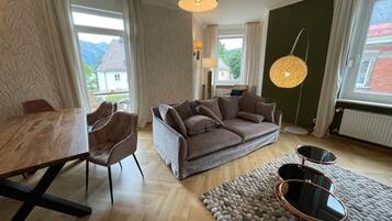 Ein modernes Wohnzimmer mit einem Holzespeisetisch, einem braunen Sofa und einem runden Couchtisch.