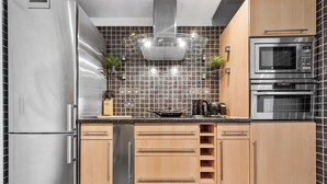 Una cocina moderna con electrodomésticos de acero inoxidable, gabinetes de madera y salpicadero de azulejos.