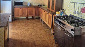 Eine Küche mit Holzausstattung, einem Kühlschrank, einem Herd und gemusterten Fliesen.