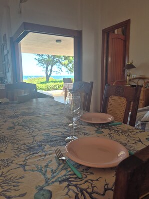 A dining table with pink plates and a wine glass, set for two, with a view of the outdoors. - Anna's house, traditional and comfortable, for those who love animals and cats (Aglientu)