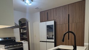 A modern kitchen with a white countertop, black faucet, and wooden cabinets.