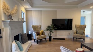 A living room with a fireplace, two armchairs, a sofa, and a television.
